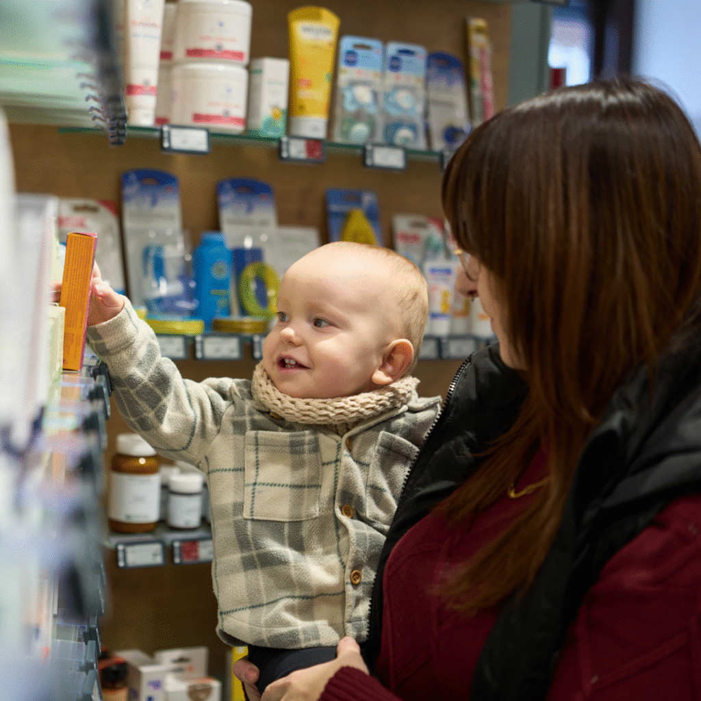 Beim Thema Mutter und Kind steht die Begleitung in der Rhön-Apotheke Kaltennordheim im Mittelpunkt, während ein Baby eine Packung hält und Nähe sucht.